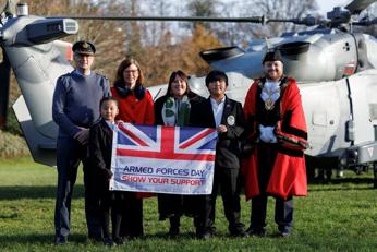 Alex Baker with representatives of the armed forces, Rushmoor Borough Council and school children holding up a Armed Forces Day flag